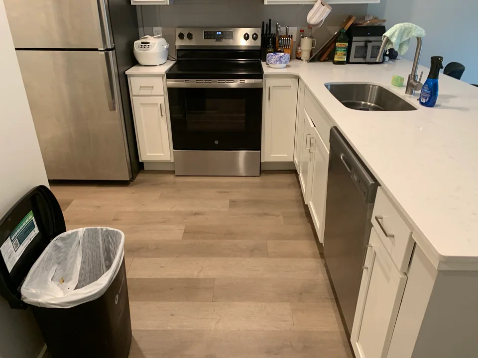 Kitchen with clear floor, white cabinets, stainless appliances, and open counters.